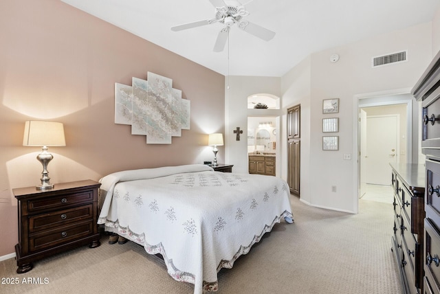 bedroom featuring ensuite bath, light colored carpet, and ceiling fan