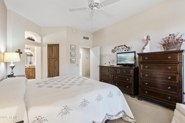 bedroom featuring ceiling fan, connected bathroom, and light carpet