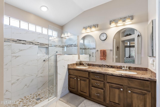 bathroom featuring lofted ceiling, tile patterned flooring, a tile shower, and vanity