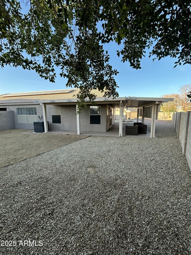 view of front of home featuring outdoor lounge area, a patio area, a fenced backyard, and central AC