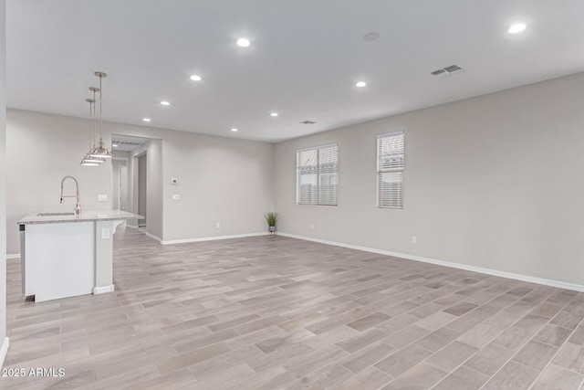 19873 W San Juan Ave, Litchfield Park, AZ 85340 - unfurnished living room with recessed lighting, baseboards, a sink, and light wood-style floors