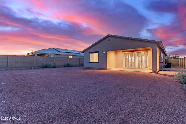 19873 W San Juan Ave, Litchfield Park, AZ 85340 - back of house at dusk with stucco siding, a fenced backyard, and a patio
