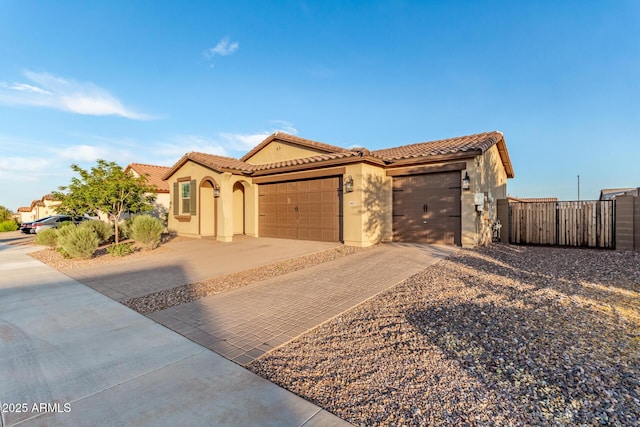 19873 W San Juan Ave, Litchfield Park, AZ 85340 - mediterranean / spanish-style house featuring stucco siding, decorative driveway, an attached garage, fence, and a tile roof