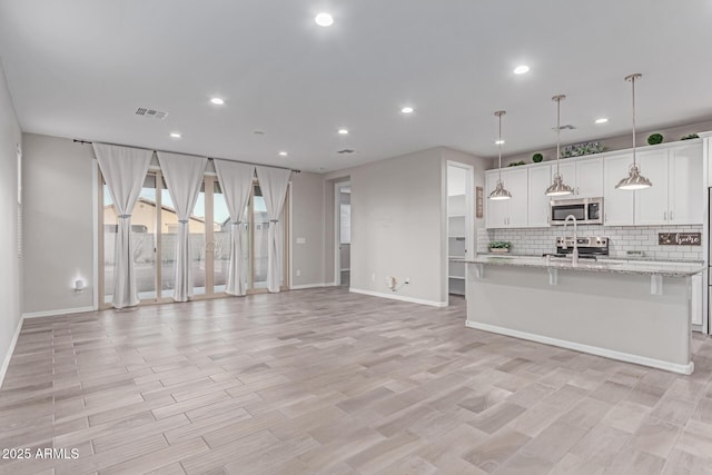 19873 W San Juan Ave, Litchfield Park, AZ 85340 - kitchen with stainless steel appliances, open floor plan, decorative backsplash, baseboards, and recessed lighting