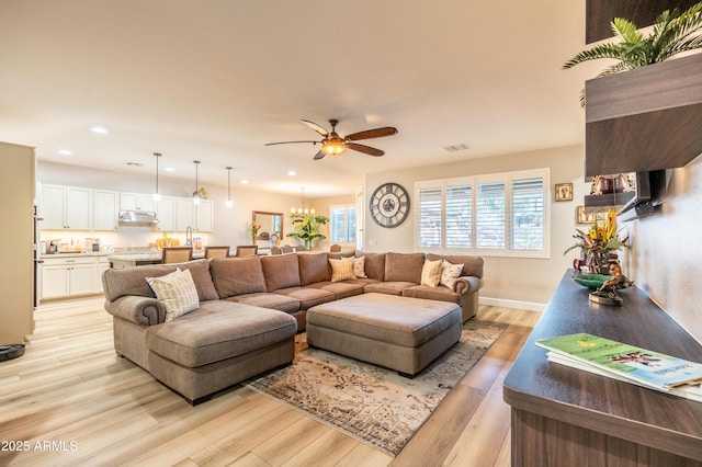 living room with light wood-style floors, visible vents, ceiling fan with notable chandelier, and recessed lighting