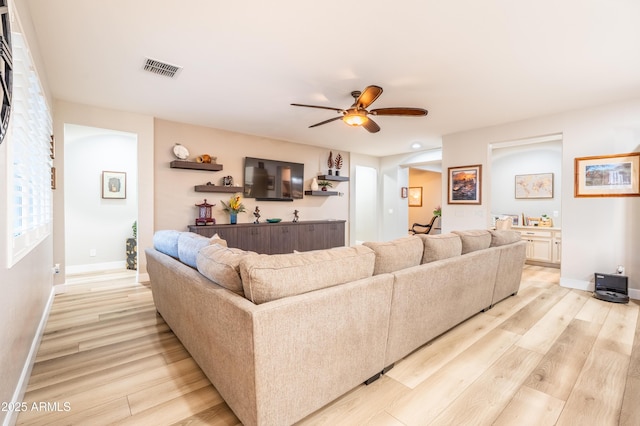 living area featuring light wood-style floors, baseboards, visible vents, and a ceiling fan