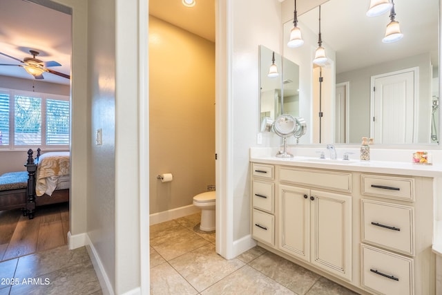 ensuite bathroom with toilet, ensuite bathroom, a ceiling fan, vanity, and baseboards