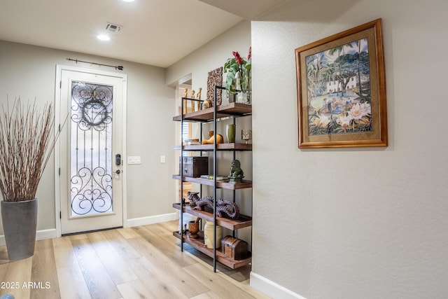 foyer entrance with visible vents, light wood-style flooring, and baseboards