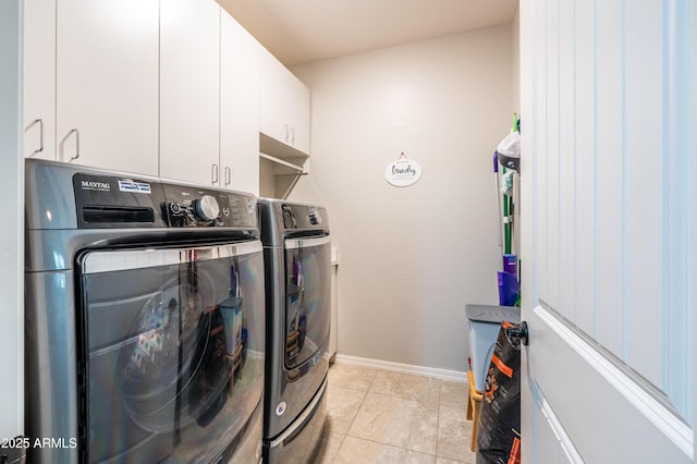 washroom with light tile patterned floors, washer and clothes dryer, cabinet space, and baseboards