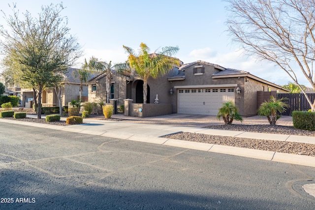 view of front of home with stucco siding, fence, a garage, driveway, and a tiled roof