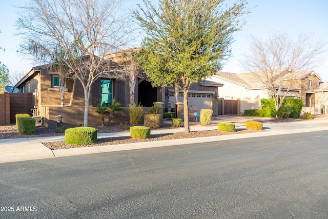 view of front of house with concrete driveway, fence, an attached garage, and stucco siding