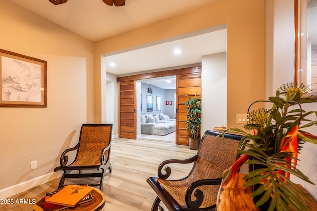 sitting room featuring light wood-style flooring, baseboards, and ceiling fan