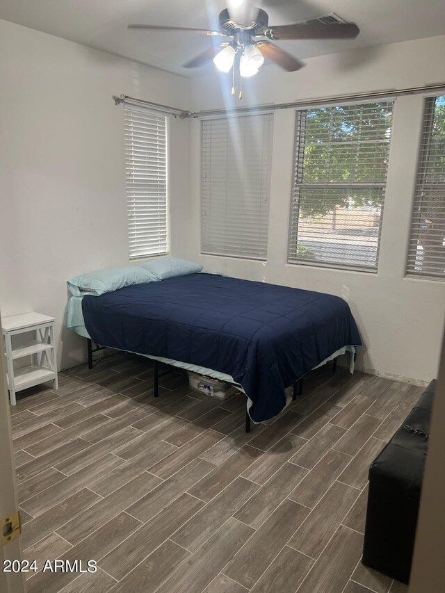 bedroom with multiple windows, ceiling fan, and hardwood / wood-style flooring