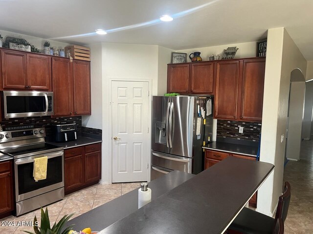 kitchen with appliances with stainless steel finishes, decorative backsplash, and light tile patterned flooring