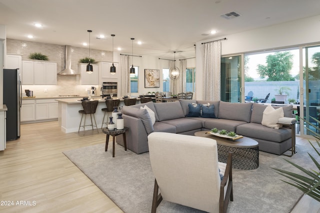 living room featuring a chandelier, visible vents, light wood finished floors, and recessed lighting