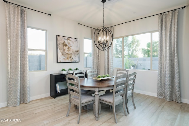 dining room with a chandelier, light wood-style flooring, and baseboards