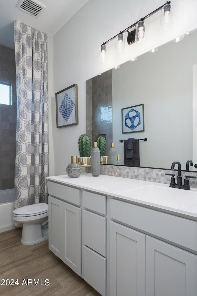bathroom with vanity, shower / bath combo with shower curtain, toilet, visible vents, and wood finished floors