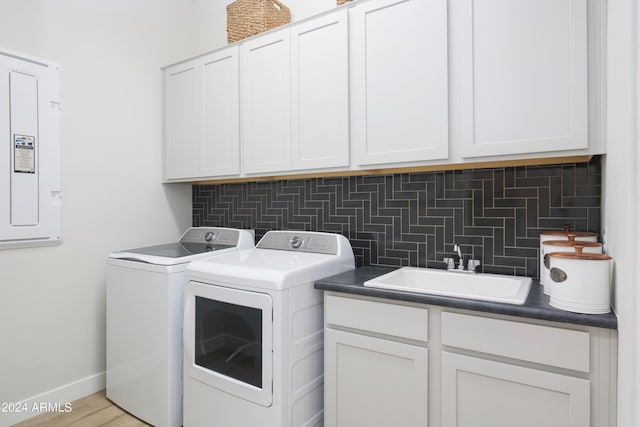 laundry area with cabinet space, electric panel, washing machine and dryer, baseboards, and a sink