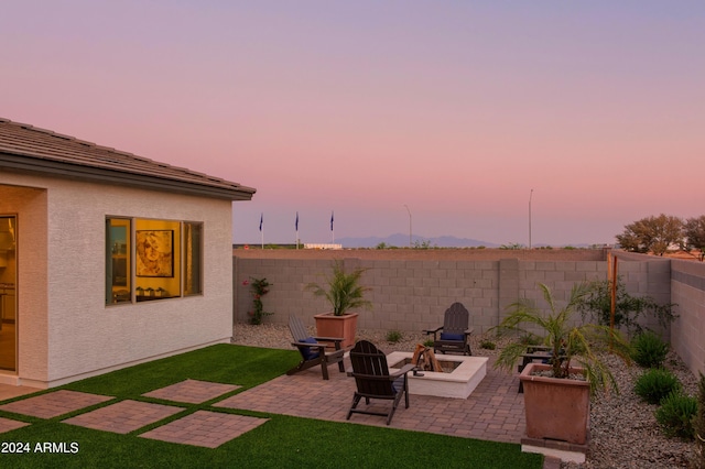 yard at dusk featuring a patio, a fire pit, and a fenced backyard