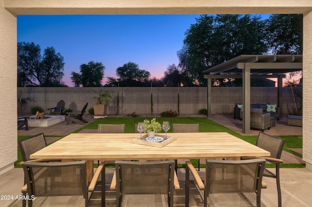 patio terrace at dusk with an outdoor living space with a fire pit, outdoor dining space, and a fenced backyard