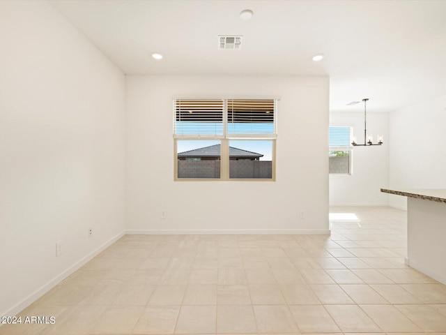 spare room with light tile patterned floors and an inviting chandelier