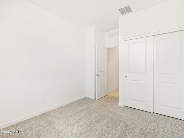 unfurnished bedroom with a closet and light carpet