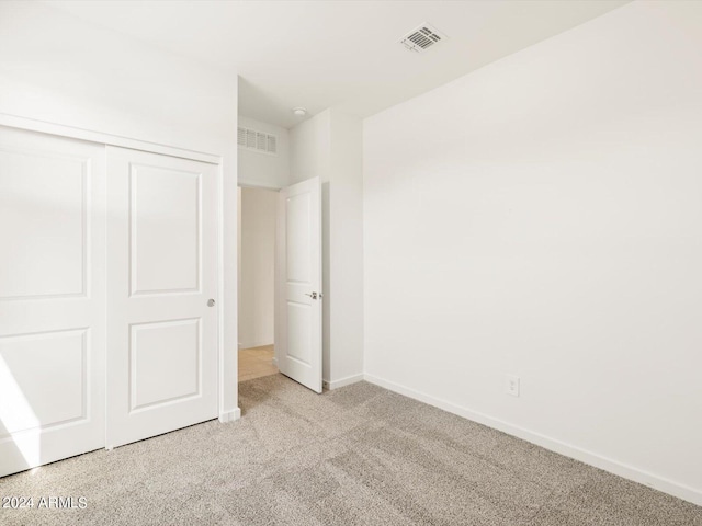 unfurnished bedroom with light carpet and a closet