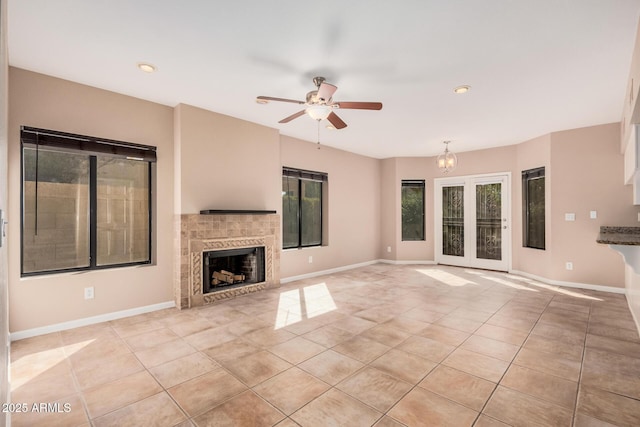 unfurnished living room with light tile patterned floors, a tile fireplace, baseboards, and ceiling fan