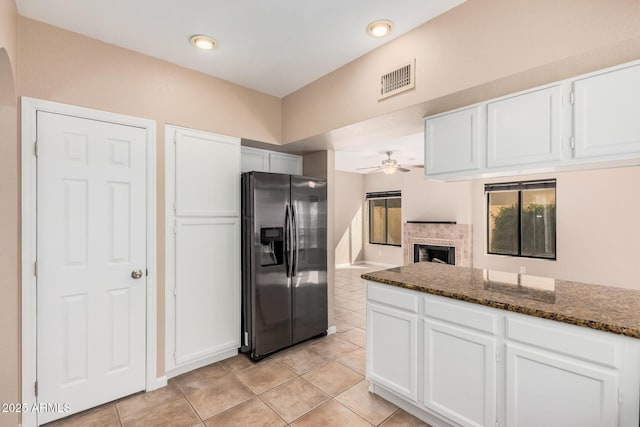 kitchen featuring a ceiling fan, visible vents, a fireplace, white cabinets, and stainless steel fridge