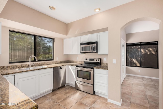 kitchen featuring a sink, stone countertops, arched walkways, appliances with stainless steel finishes, and white cabinets