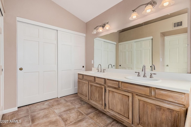 full bath with tile patterned floors, vaulted ceiling, visible vents, and a sink