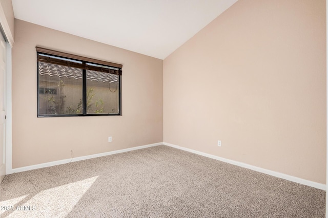 empty room with baseboards, lofted ceiling, and carpet