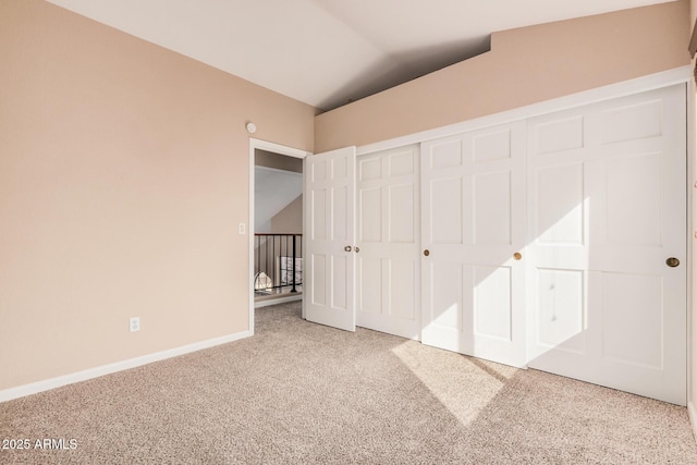 unfurnished bedroom featuring a closet, baseboards, carpet, and lofted ceiling