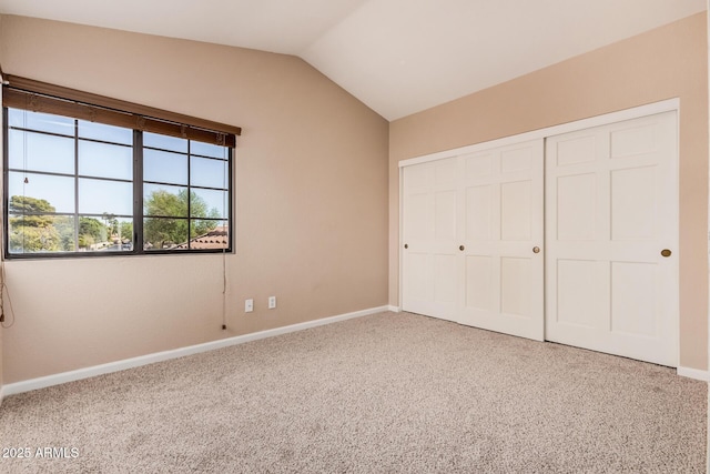 unfurnished bedroom with baseboards, lofted ceiling, a closet, and carpet flooring