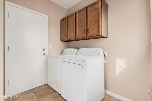 clothes washing area featuring light tile patterned floors, cabinet space, baseboards, and separate washer and dryer