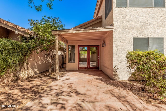 doorway to property with a patio, a tiled roof, fence, and stucco siding