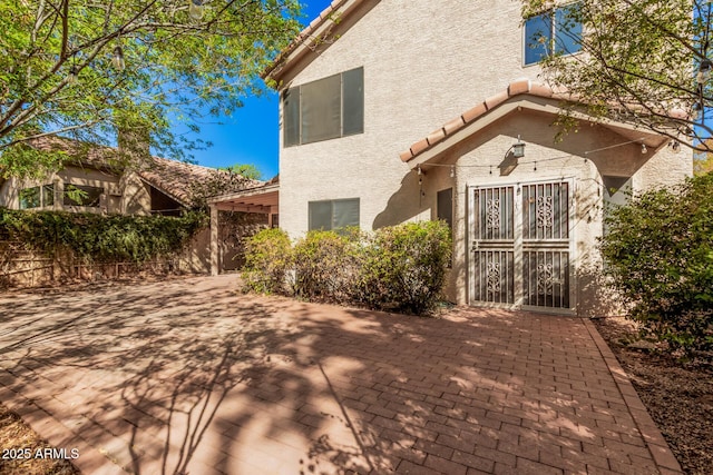 exterior space featuring stucco siding, fence, a patio area, and a tiled roof