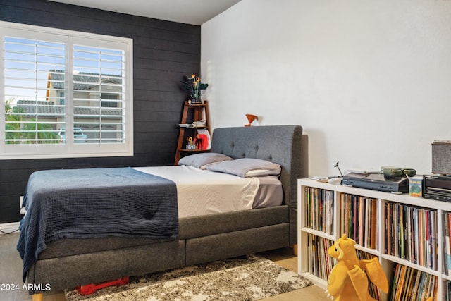 bedroom with light wood-type flooring and wood walls