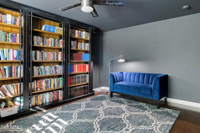 living area with dark wood-type flooring and ceiling fan