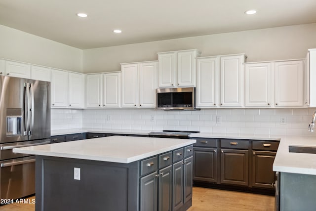 kitchen featuring appliances with stainless steel finishes, a center island, decorative backsplash, and white cabinets