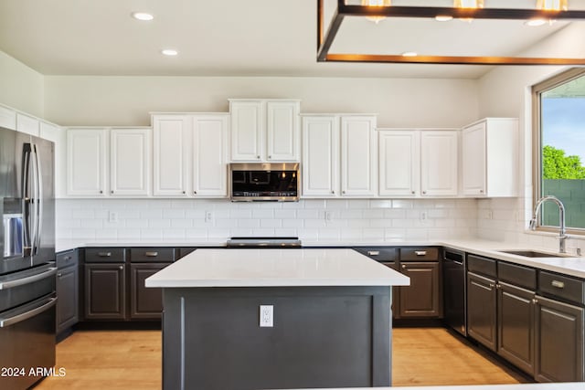 kitchen featuring white cabinetry, stainless steel appliances, sink, and a kitchen island