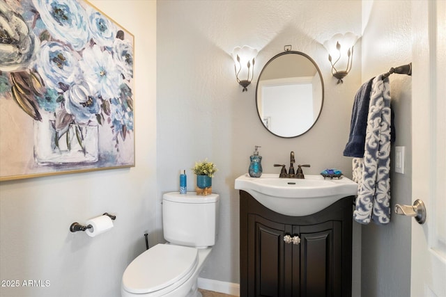 half bathroom with toilet, baseboards, and vanity