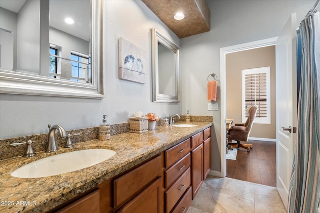 full bath featuring double vanity, tile patterned floors, a sink, and baseboards