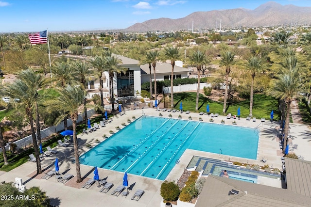 community pool with a patio area, fence, and a mountain view