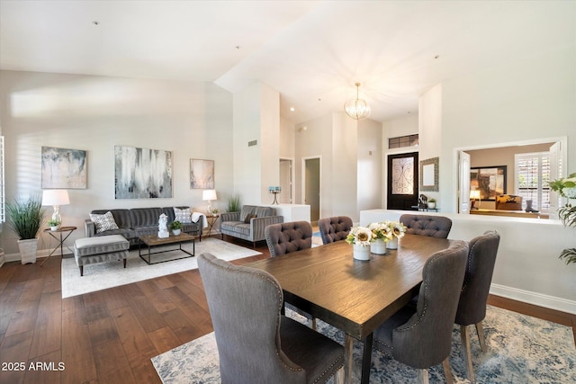 dining area with dark wood-style floors, baseboards, and high vaulted ceiling