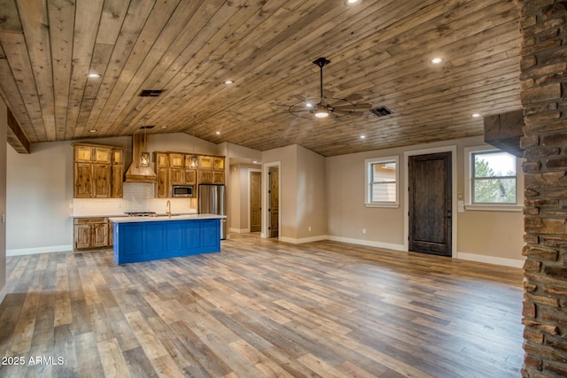 kitchen featuring decorative backsplash, appliances with stainless steel finishes, a kitchen island with sink, dark wood-type flooring, and pendant lighting