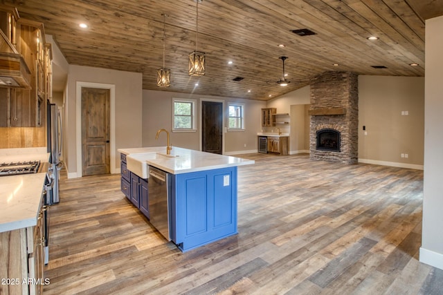 kitchen featuring pendant lighting, a center island with sink, sink, blue cabinetry, and stainless steel appliances