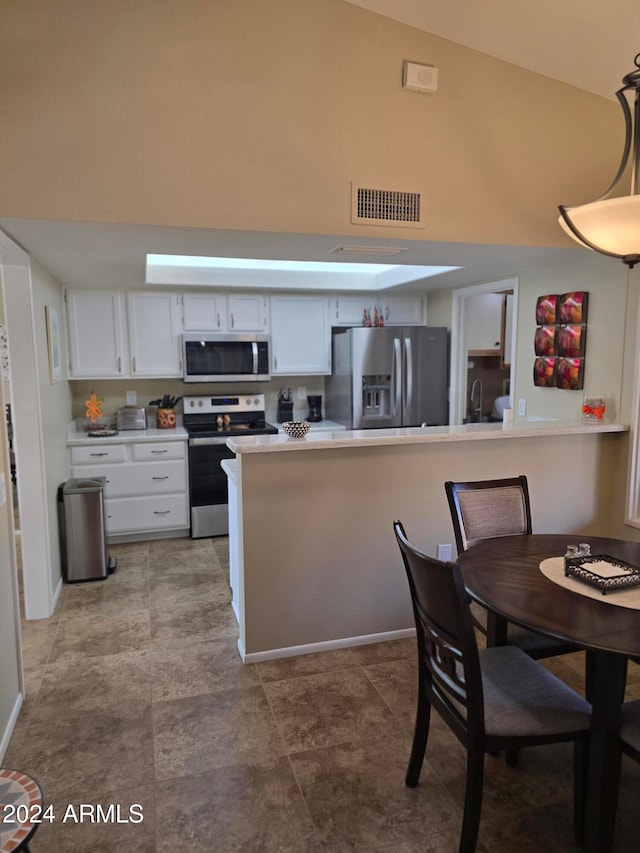 kitchen featuring high vaulted ceiling, sink, appliances with stainless steel finishes, decorative light fixtures, and white cabinetry