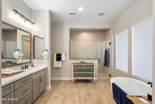 bathroom with wood-type flooring, vanity, and plus walk in shower