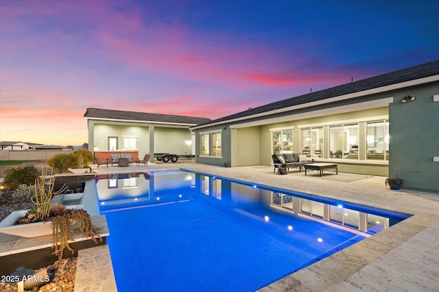 pool at dusk featuring an outdoor living space and a patio area